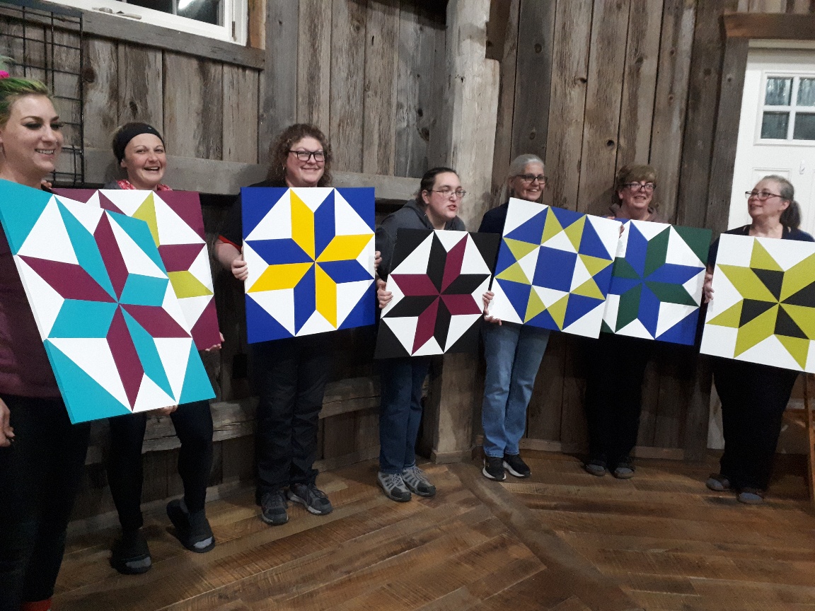 A group of women display their barn quilts