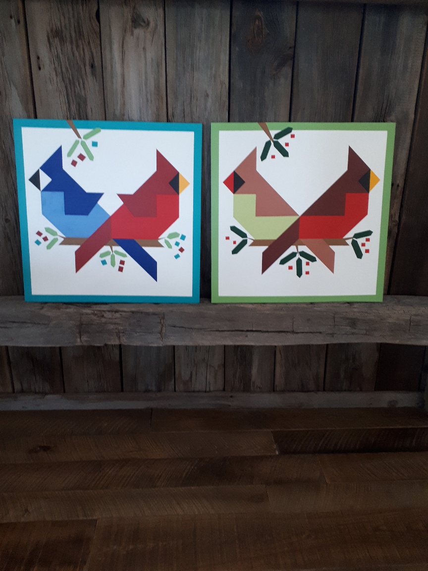 Two barn quilts that have  either a male and female cardinal or a blue jay and male cardinal 
